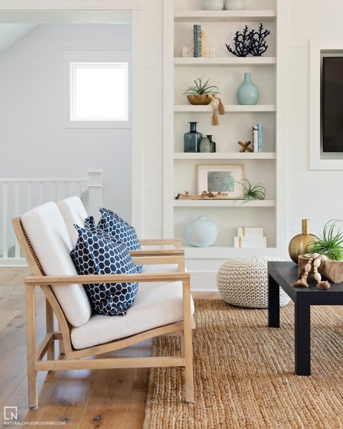 hardwood floors in living room with white chairs, shelves, trinkets, and table