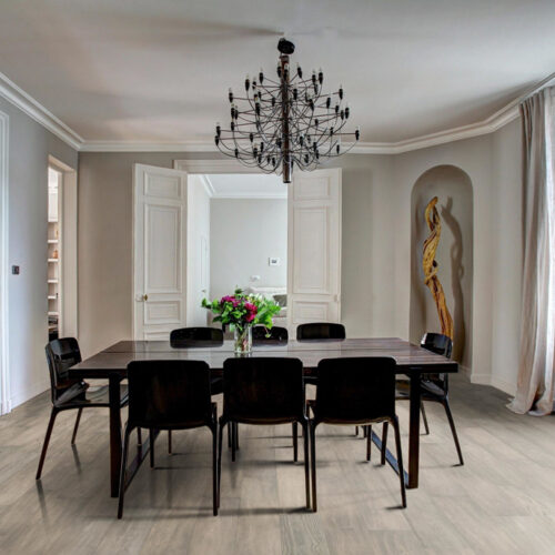 hardwood floors in dining room with black dining table, chairs, chandelier. vase with flowers, and gold sculpture