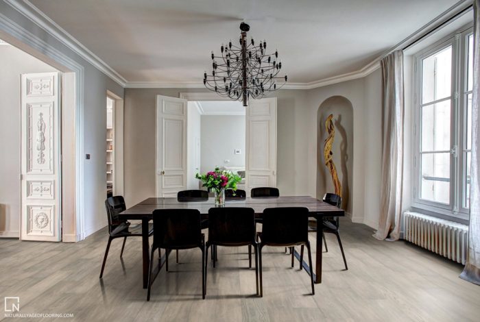 hardwood floors in dining room with black dining table, chairs, chandelier. vase with flowers, and gold sculpture