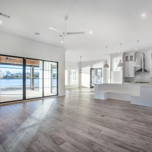 hardwood floors in empty kitchen and living area with windows overlooking a lake