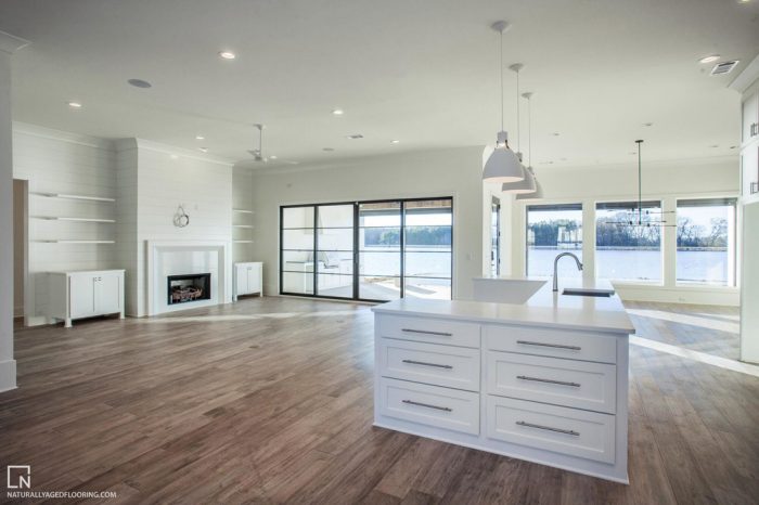 hardwood floors in kitchen overlooking empty living space with windows and a lake outside