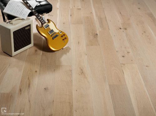 hardwood floor with electric guitar, amp, sheet music, and black ottoman