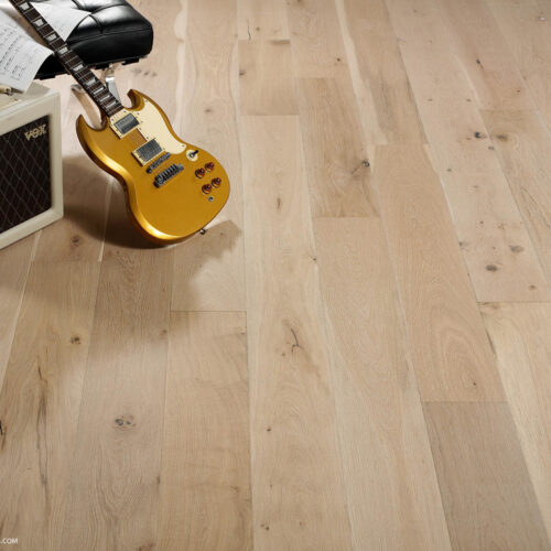 hardwood floor with electric guitar, amp, sheet music, and black ottoman