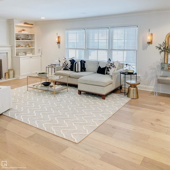 hardwood floor in living room with white couch, table, rug, and bookcase
