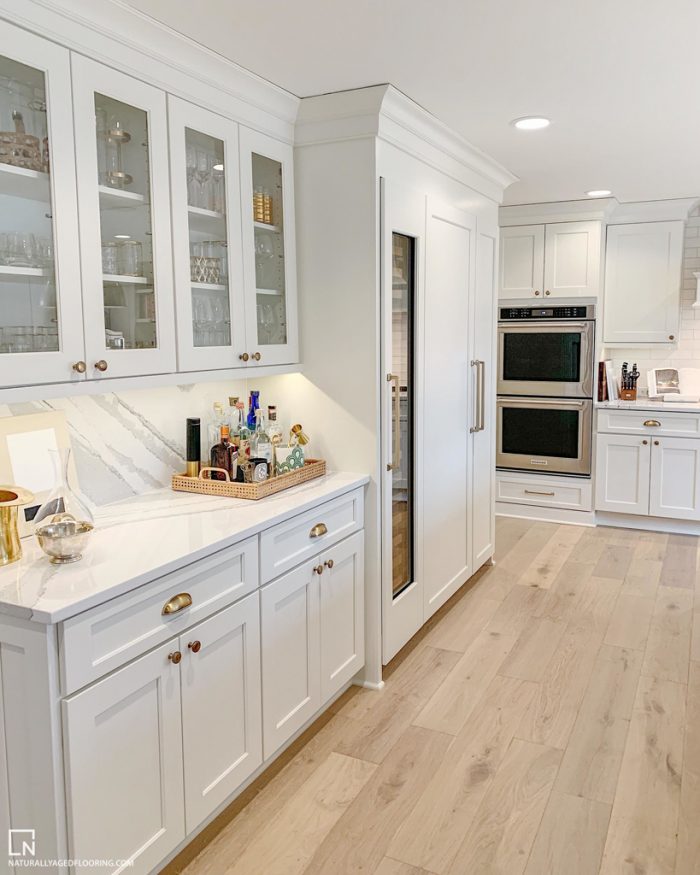 hardwood floor in white kitchen with cabinets, counter, and ovens