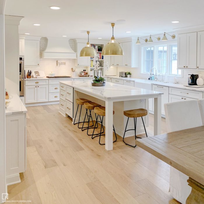 hardwood floor in fully furnished white kitchen and kitchen island with stools