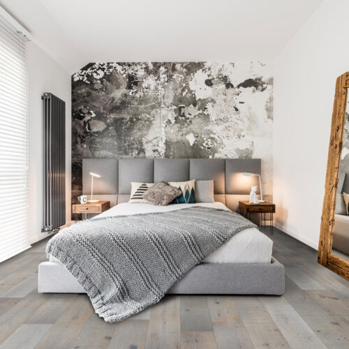 hardwood floor in gray bedroom with bed, large mirror and window