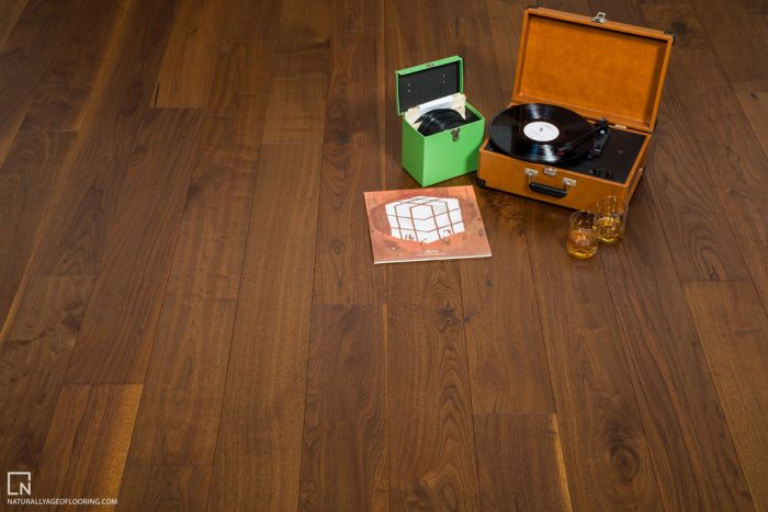 hardwood floor withorange portable record player, green record box, records, and two liquor glasses