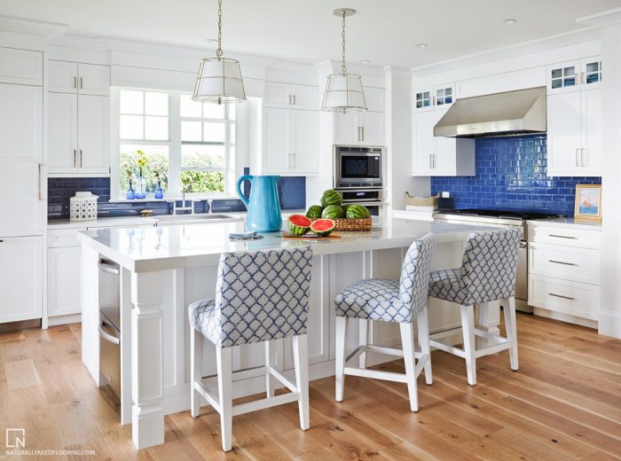 hardwood floors in white kitchen with kitchen island and stools