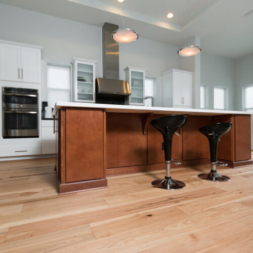 low angle of hardwood floors in fully equiped kitchen with counter bar and stools