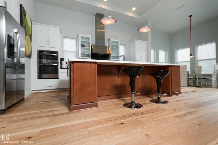 low angle of hardwood floors in fully equiped kitchen with counter bar and stools