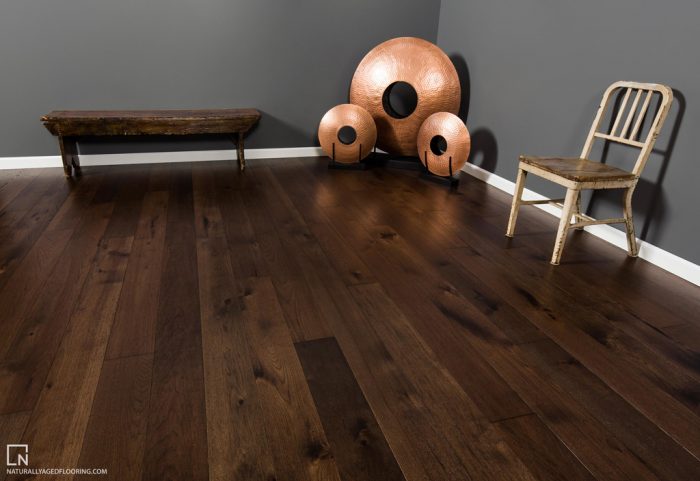 hardwood floors in corner of room with a bench, chair, and three copper sculptures