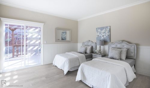 hardwood floors in all white bedroom with two beds