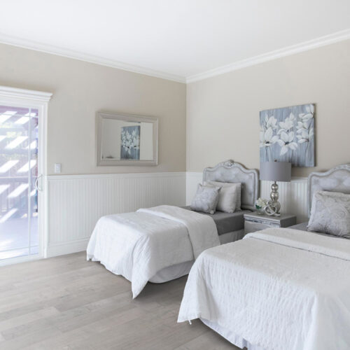hardwood floors in all white bedroom with two beds