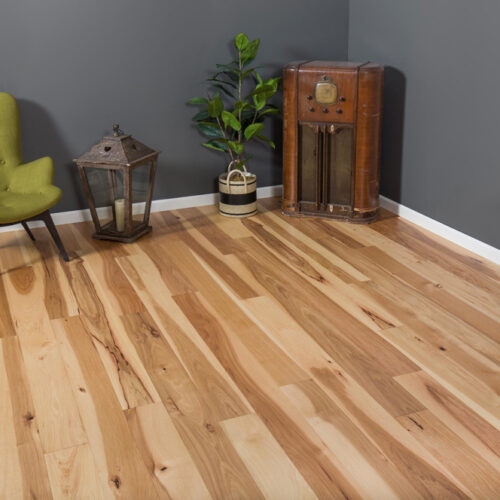 hardwood floors in corner of room with a chair, table, lanterns, plant, and old radio