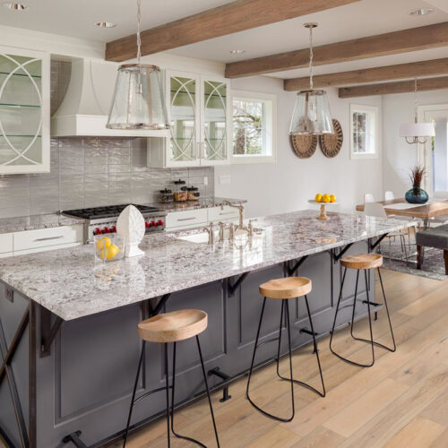 hardwood floors in kitchen with counter and stools and small kitchen table by glass doors