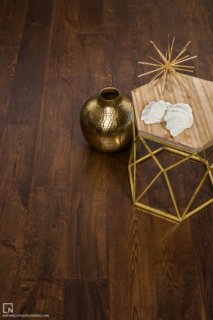 hardwood floor with gold colored table, vase, and sculpture