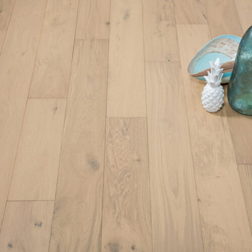 hardwood floor with green vase, green bottle, and white ceramic pineapple