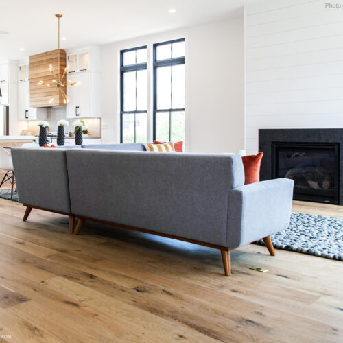 hardwood floor in living room with couch and fireplace and kitchen in the background