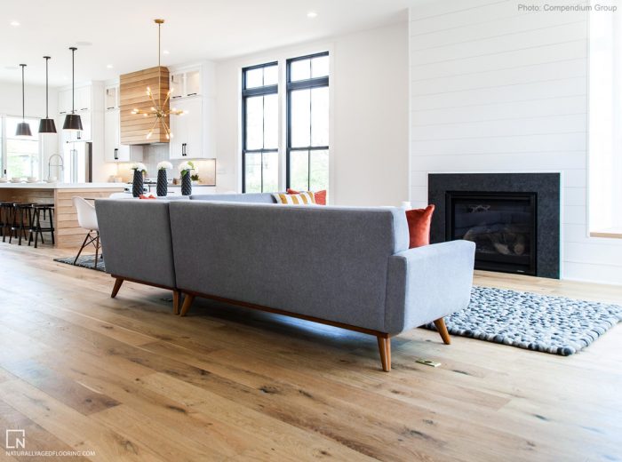 hardwood floor in living room with couch and fireplace and kitchen in the background