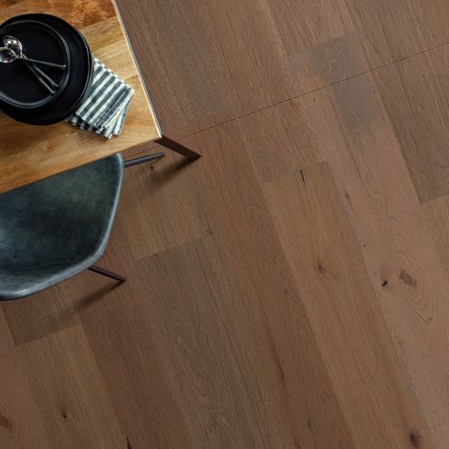 overhead shot of hardwood flooring with a glipse of a kitchen table, plate setting, and chair