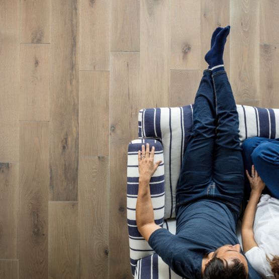 overhead shot of hardwood flooring with a couch and two people sitting on it