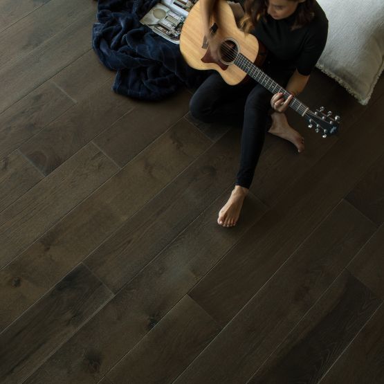 overhead view of hardwood flooring and a person playing guitar sitting on the floor