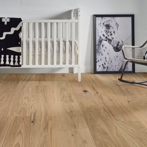 hardwood flooring in baby nursery with black and white decor, crib, blanket, rocking chair and painting of a horse