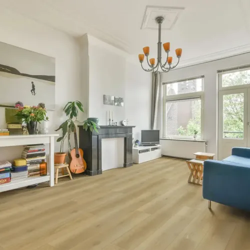 Medford warm honey-caramel waterproof luxury vinyl plank flooring in an eclectic dining room with blue sofa